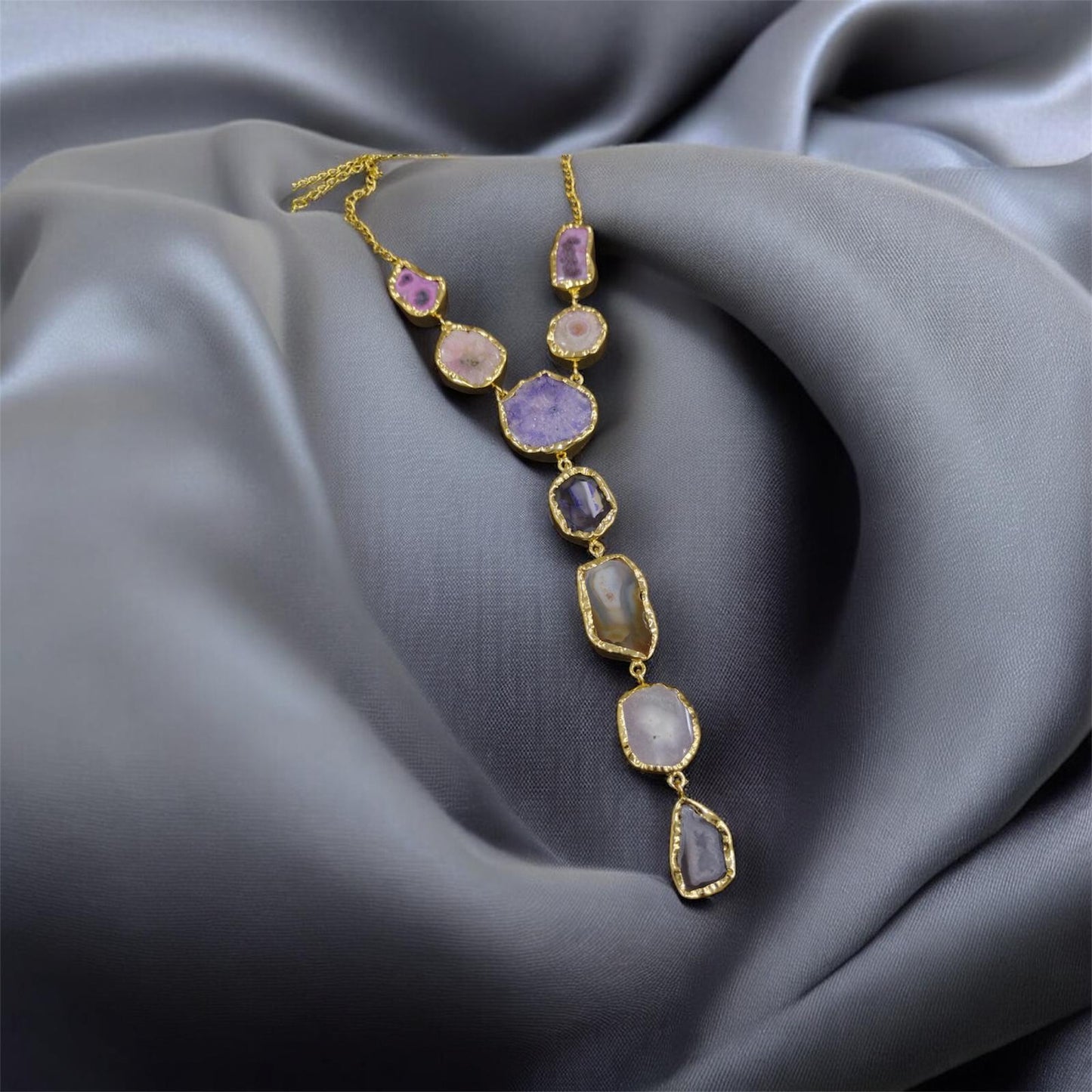 Necklace with purple and clear gemstones on a gray fabric background