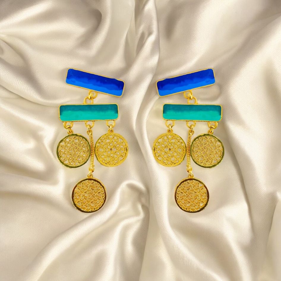 Pair of earrings with blue and green accents on a satin background