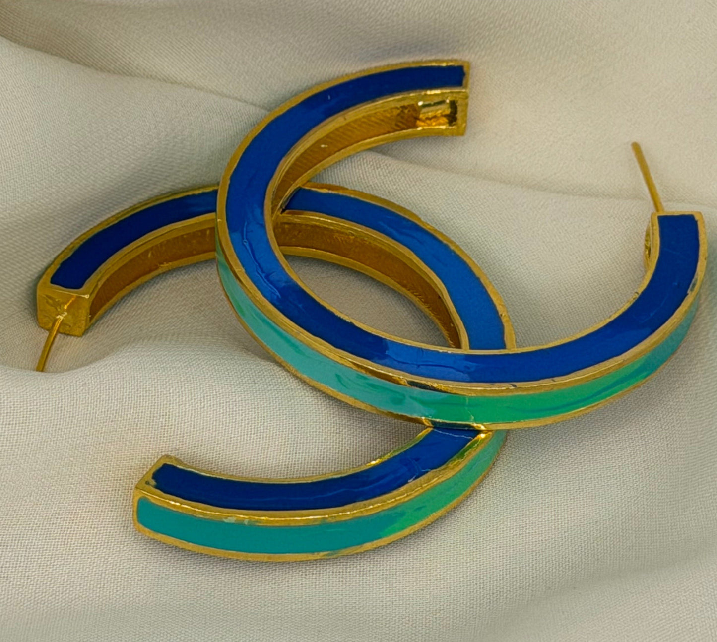 Gold and blue hoop earrings on a satin surface