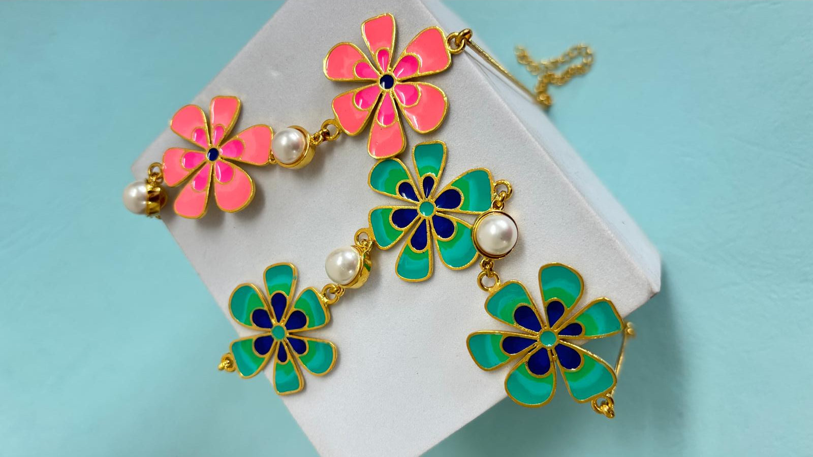 Colorful flower-shaped earrings with pearls on a light blue background