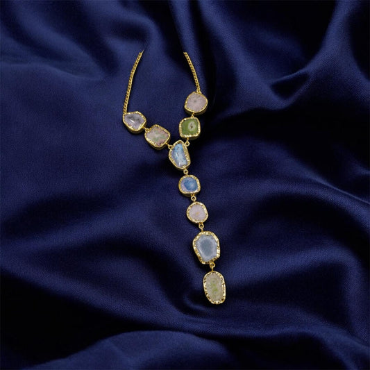 Gold necklace with gemstones on a dark blue fabric background