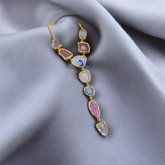 Gold necklace with colorful gemstones on a gray fabric background