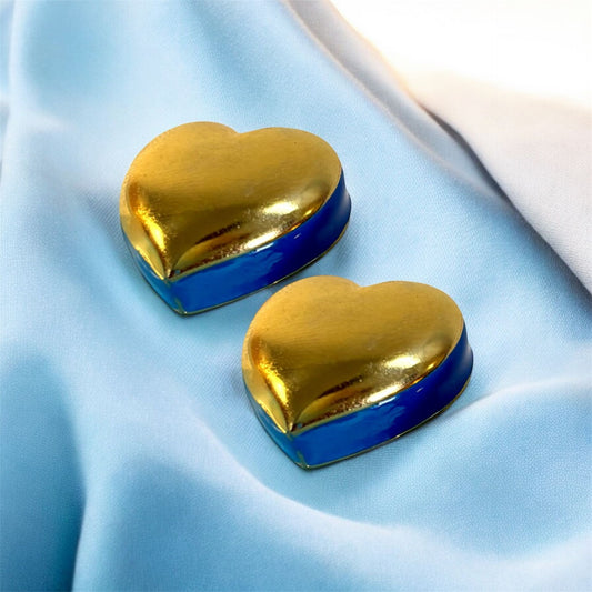 Heart-shaped gold and blue earrings on a light blue fabric background