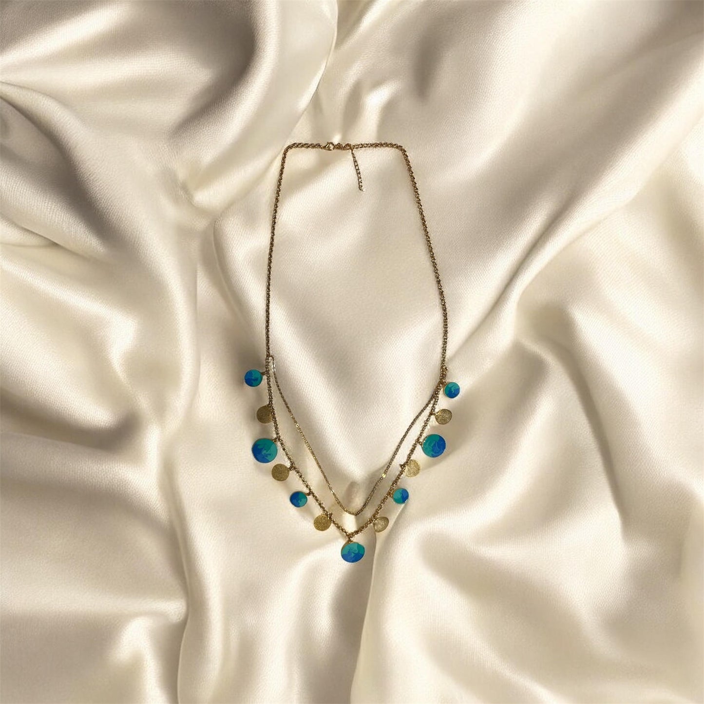 Necklace with blue and gold beads on a satin surface