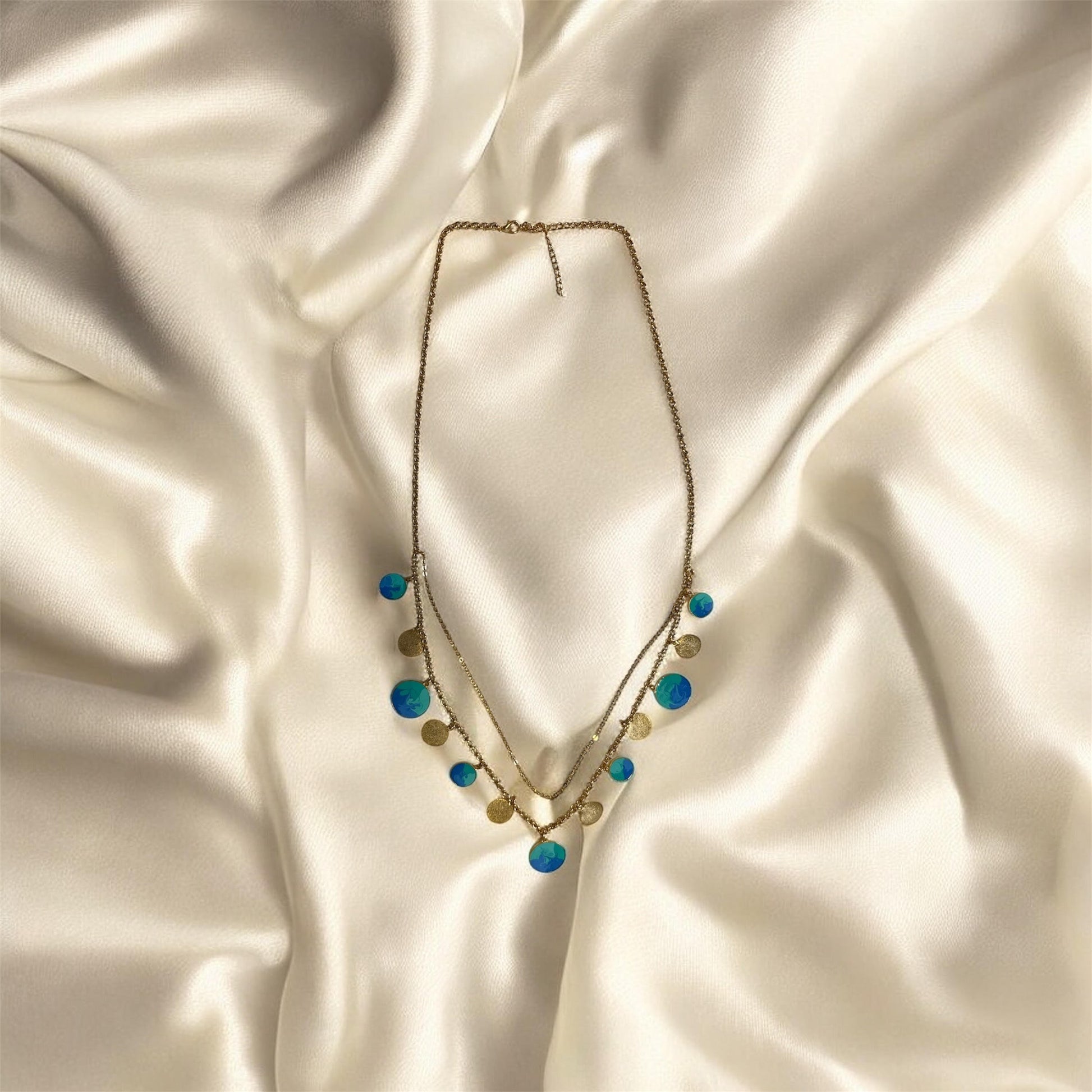 Necklace with blue and gold beads on a satin surface
