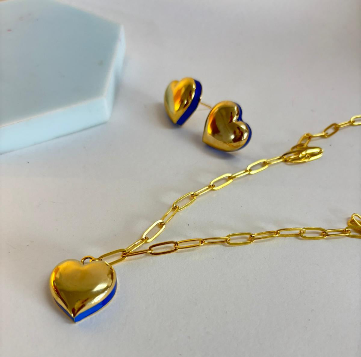 Gold heart-shaped necklace with blue accents on a light gray background