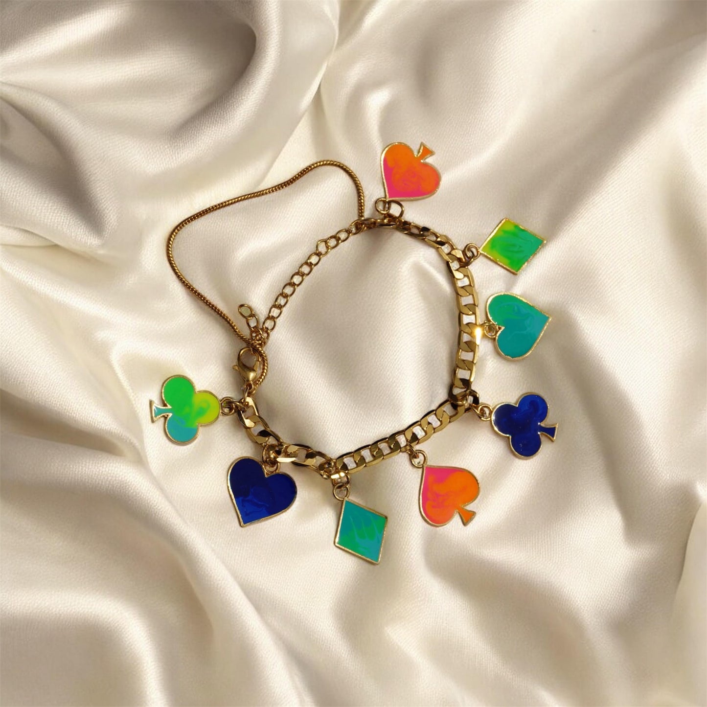 Gold bracelet with colorful charms on a satin surface