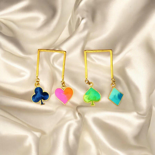 Gold earrings with colorful heart, clover, and spade charms on a satin background