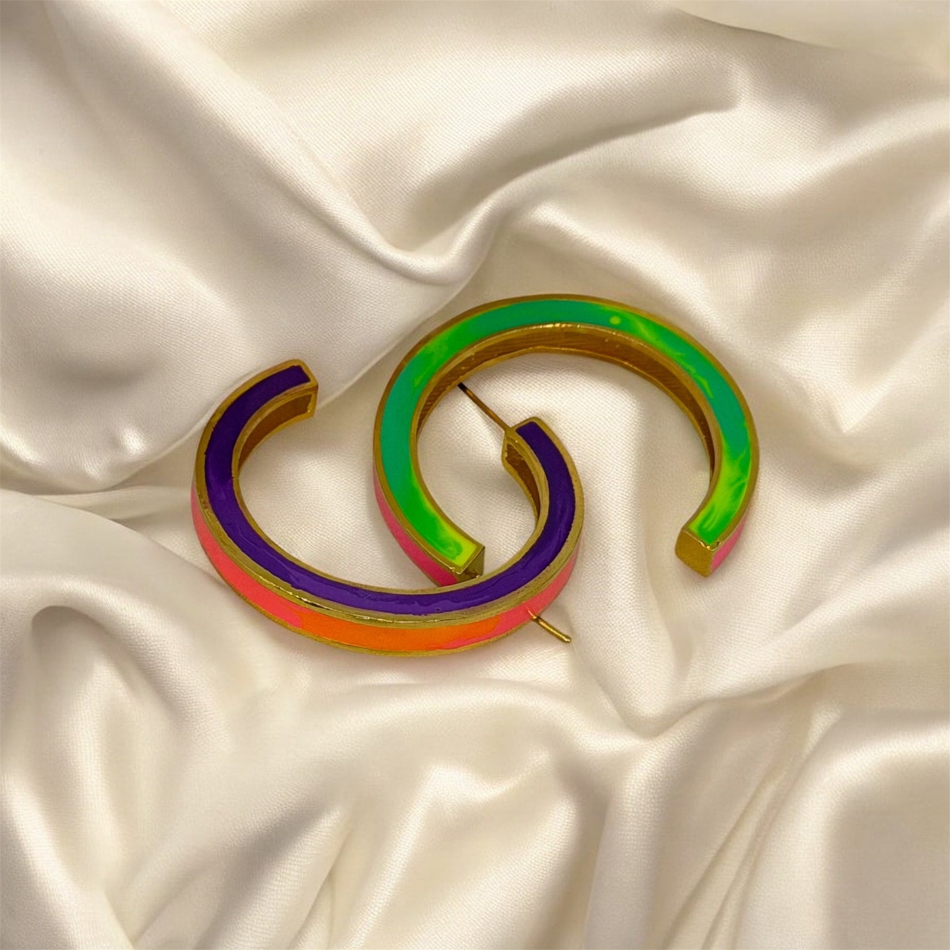 Colorful brooch with a design resembling the number '69' on a satin background