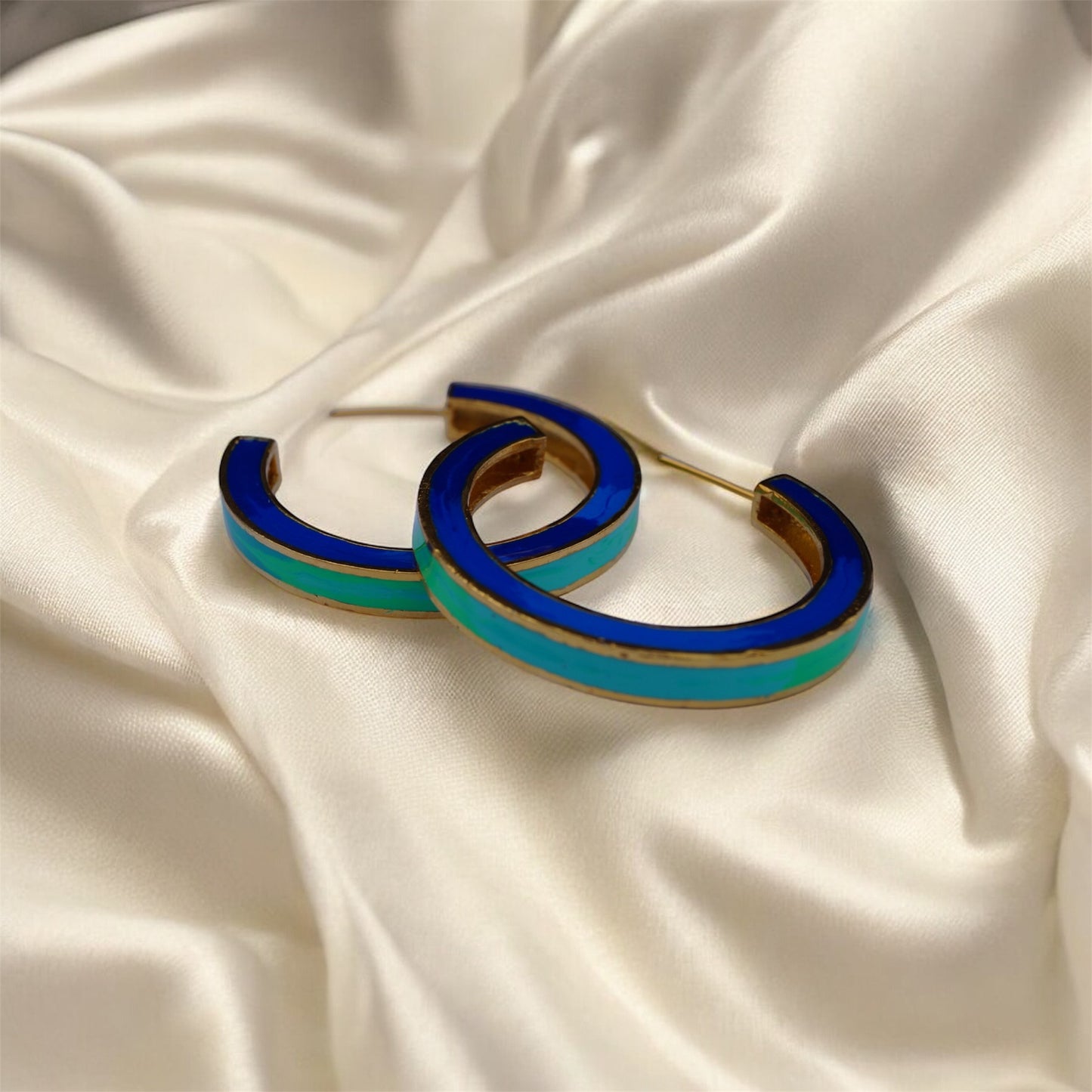 Blue and gold hoop earrings on a beige fabric background