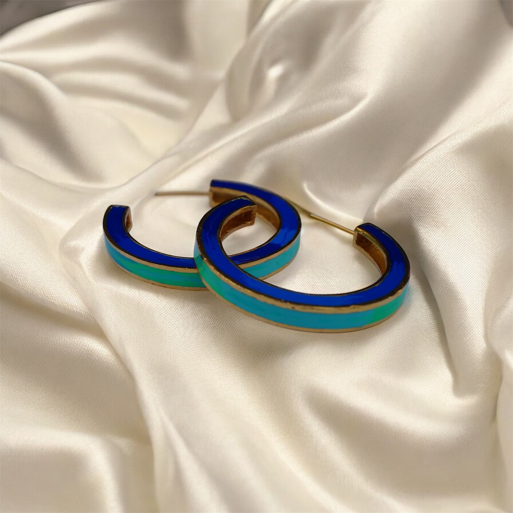 Blue and gold hoop earrings on a beige fabric background