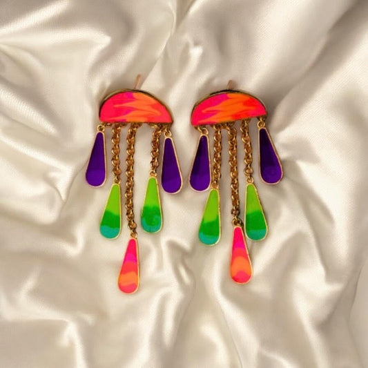 Colorful earrings with rainbow teardrop design on a satin background