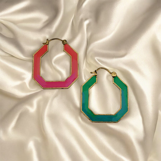 Two hoop earrings, one pink and one green, on a satin surface.