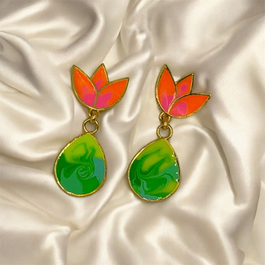 Colourful earrings with lotus-shaped tops on a satin surface