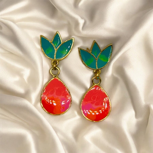 Colorful earrings with green leaves on a satin background