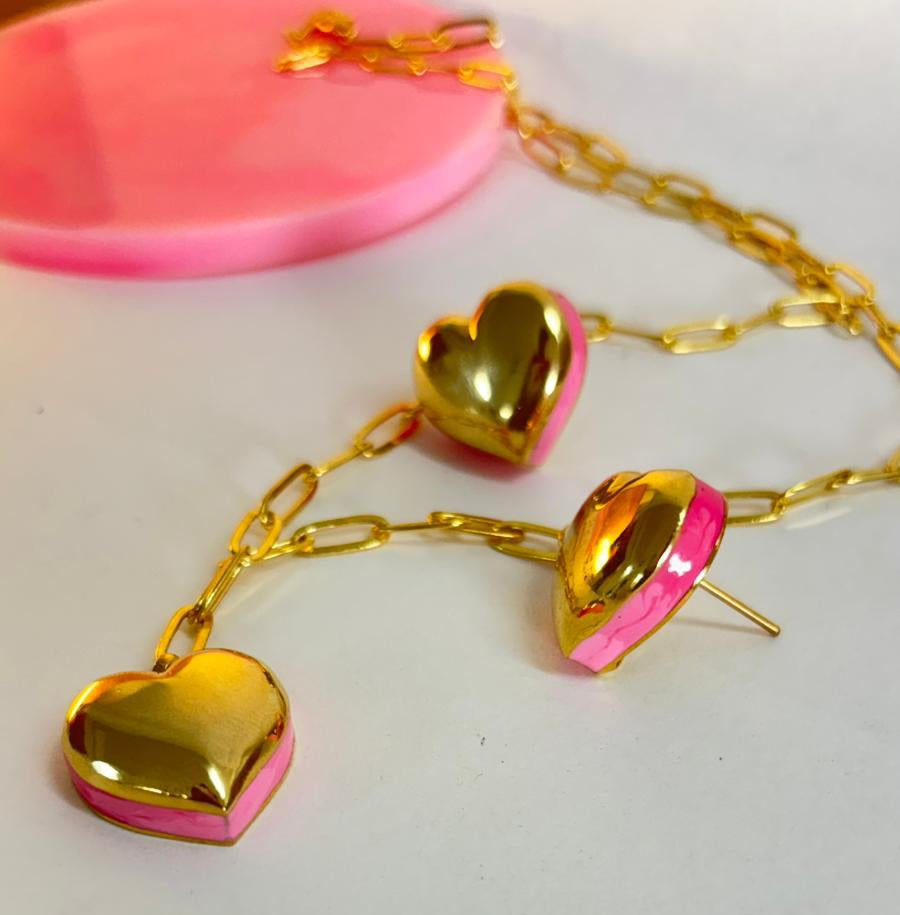 Gold heart-shaped earrings with pink centers on a white background