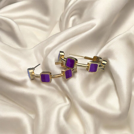 Gold and purple earrings on a satin surface