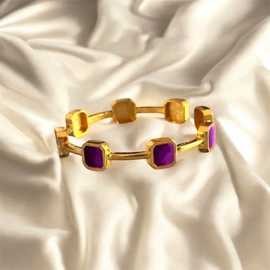 Gold bracelet with purple stones on a satin background