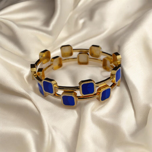 Gold bracelet with blue square stones on a satin background