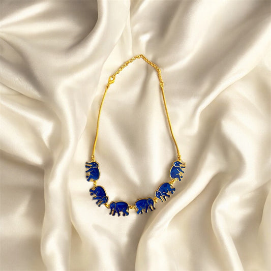 Gold necklace with blue elephant pendants on a satin background
