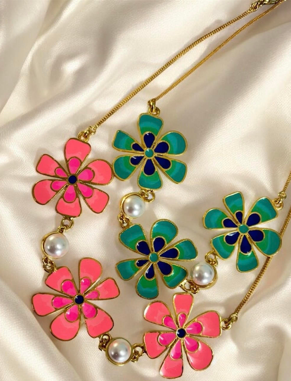 Necklace with pink and green floral pendants on a satin background