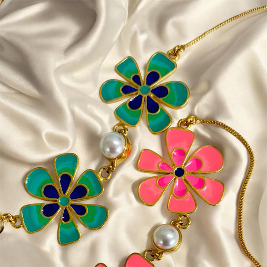 Colorful flower-shaped pendants on gold chains with pearls on a satin background